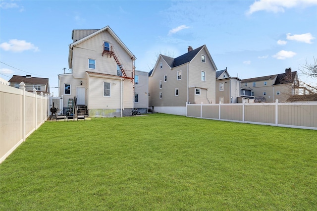 back of house featuring a yard and a fenced backyard