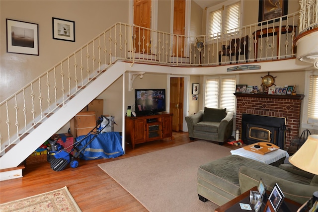 living area featuring a wealth of natural light, stairs, a high ceiling, and wood finished floors