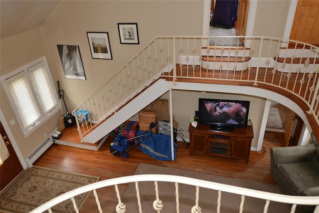 living room featuring arched walkways, stairway, baseboard heating, and wood finished floors