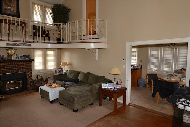 living area with a fireplace, wood finished floors, and a towering ceiling