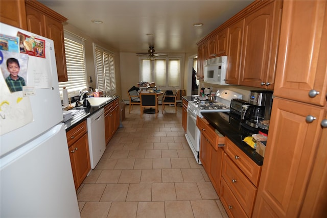 kitchen featuring light tile patterned floors, dark countertops, a ceiling fan, a sink, and white appliances