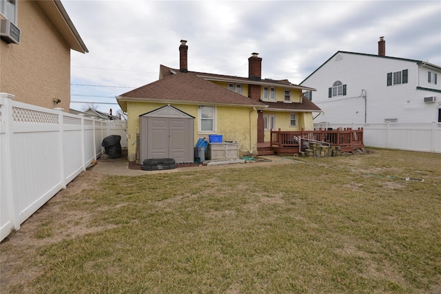 rear view of property featuring a shed, a lawn, a fenced backyard, and an outdoor structure