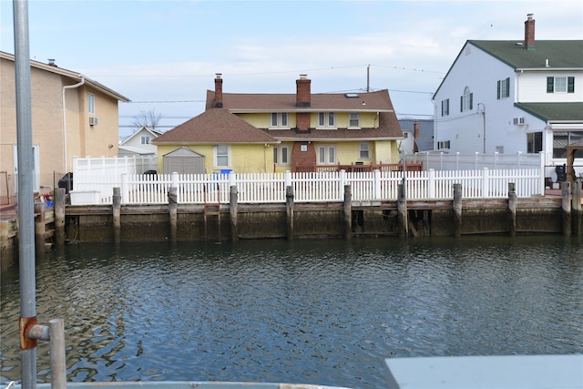 rear view of property with a water view, fence private yard, and a residential view