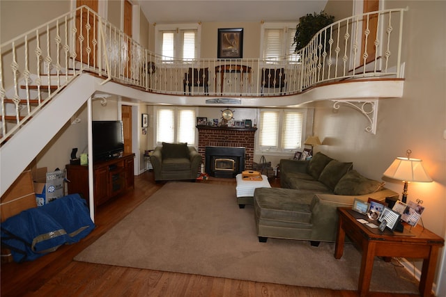 living area with stairway, wood finished floors, and a towering ceiling