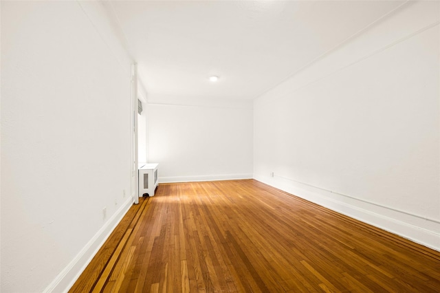 spare room featuring hardwood / wood-style floors, radiator heating unit, and baseboards