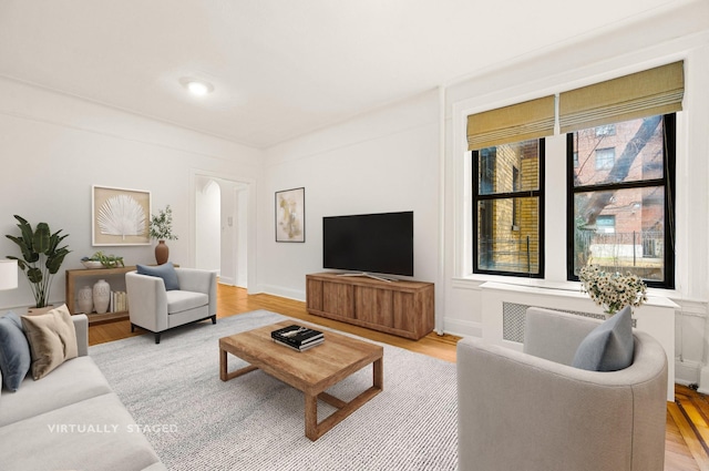 living area with light wood finished floors, arched walkways, and baseboards