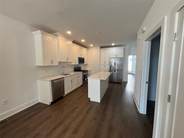 kitchen featuring a sink, dark wood-type flooring, appliances with stainless steel finishes, and white cabinetry