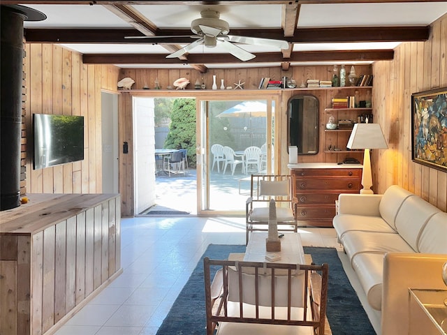 living area with ceiling fan, beam ceiling, and wooden walls