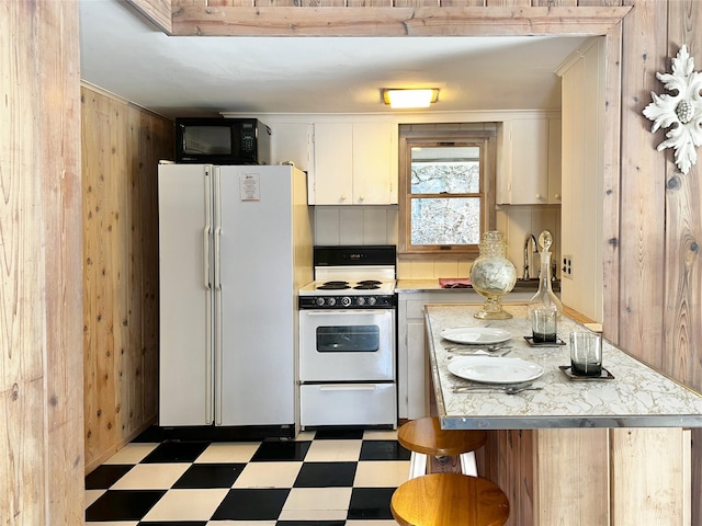 kitchen with white appliances, light countertops, light floors, and wood walls