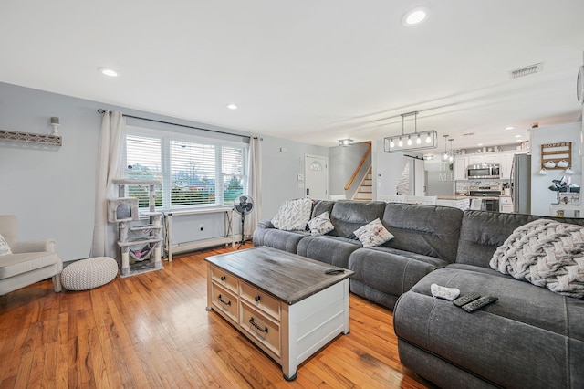 living room with stairs, light wood-style flooring, visible vents, and recessed lighting