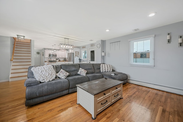 living area with visible vents, stairs, baseboard heating, light wood-style floors, and recessed lighting