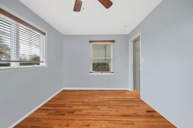 empty room featuring wood finished floors, a ceiling fan, and baseboards