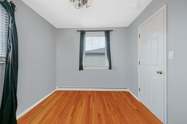 empty room with baseboards, baseboard heating, and light wood-style floors