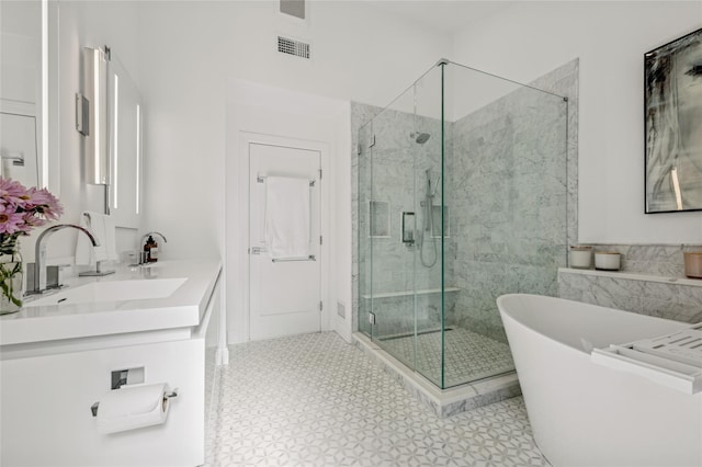 bathroom with visible vents, a freestanding bath, double vanity, a stall shower, and a sink