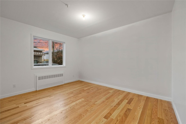 spare room with light wood-style floors, radiator, and baseboards