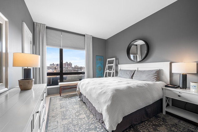 bedroom with a view of city and wood finished floors