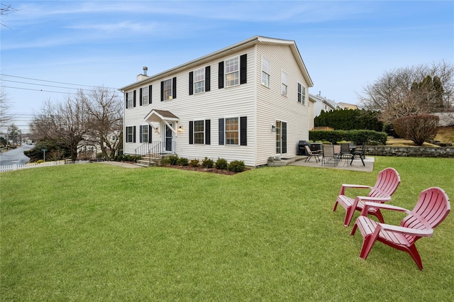 view of front of home with entry steps, a patio area, a chimney, and a front lawn