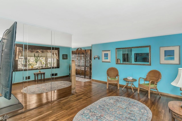 sitting room with baseboards, wood finished floors, and crown molding