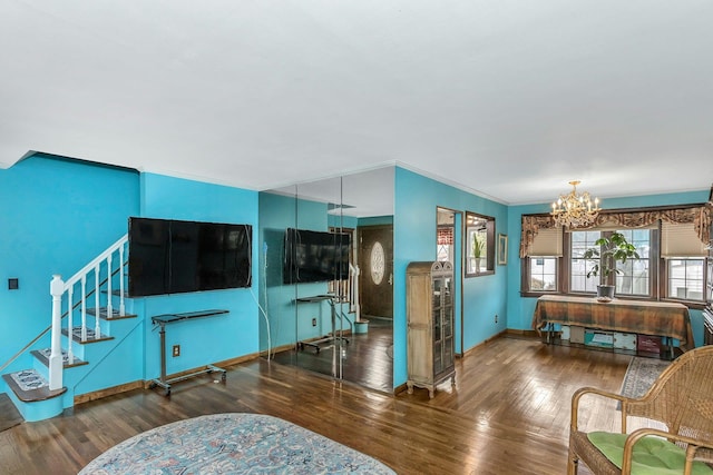 living area featuring baseboards, stairway, wood finished floors, an inviting chandelier, and crown molding