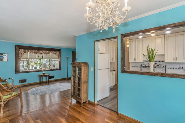 interior space featuring dark wood-style floors, crown molding, tasteful backsplash, dark countertops, and freestanding refrigerator