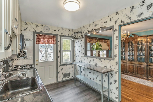 kitchen featuring wood finished floors, stove, a sink, and wallpapered walls