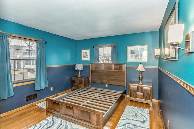 bedroom with baseboards, visible vents, and wood finished floors