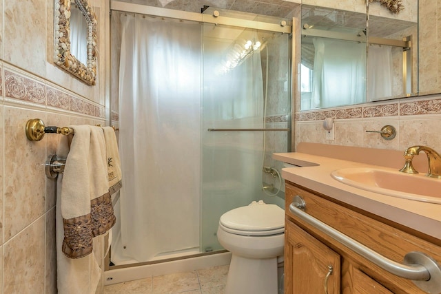 full bathroom featuring a stall shower, toilet, tile patterned floors, vanity, and tile walls