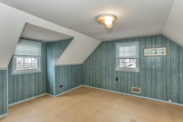 additional living space featuring a healthy amount of sunlight, visible vents, concrete flooring, and lofted ceiling