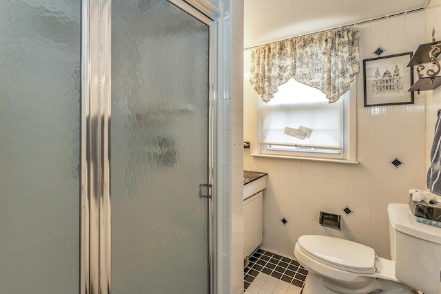 bathroom featuring toilet, a shower stall, tile walls, and tile patterned floors