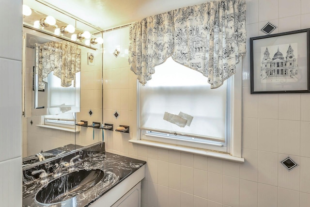 bathroom with a wealth of natural light, vanity, and tile walls