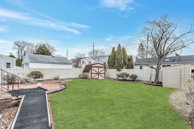 view of yard featuring a patio area, a fenced backyard, an outdoor structure, and a shed