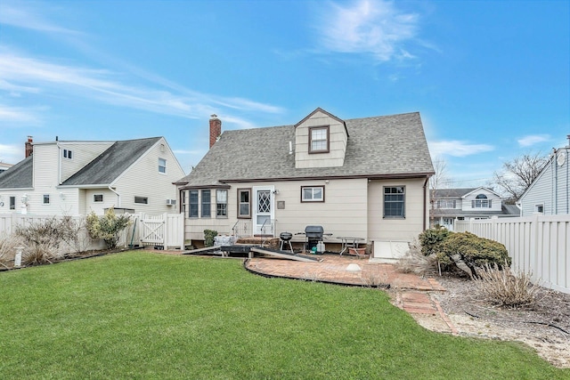 rear view of house with a gate, a fenced backyard, a yard, and a patio