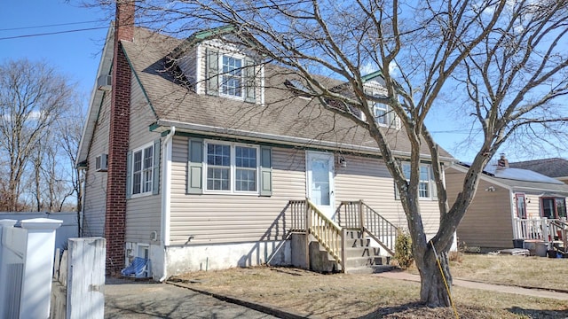 new england style home featuring a wall unit AC and a shingled roof