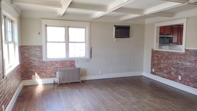 spare room featuring radiator, an AC wall unit, wood finished floors, coffered ceiling, and beamed ceiling