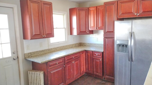 kitchen with stainless steel fridge, dark brown cabinets, backsplash, and radiator heating unit