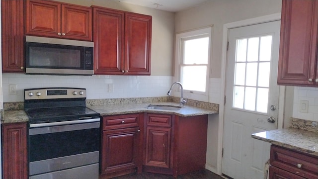 kitchen with dark brown cabinets, appliances with stainless steel finishes, a sink, and tasteful backsplash