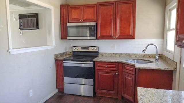 kitchen featuring stainless steel appliances, a sink, dark brown cabinets, and light stone countertops