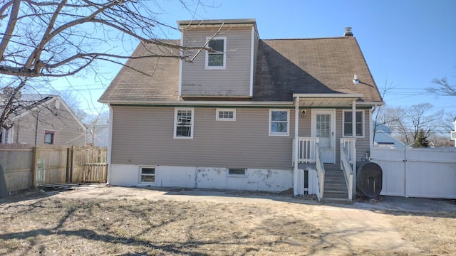 back of house with a shingled roof, fence, and heating fuel