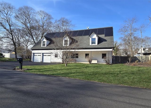 cape cod house featuring a porch, aphalt driveway, solar panels, fence, and a front yard