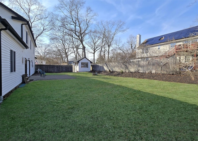 view of yard with a patio area, a fenced backyard, a storage shed, and an outbuilding