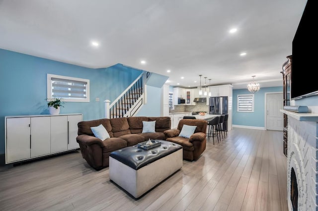 living room featuring a notable chandelier, recessed lighting, stairway, light wood-style floors, and baseboards