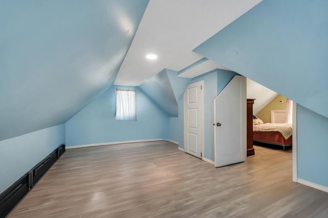 additional living space with lofted ceiling, wood finished floors, and baseboards