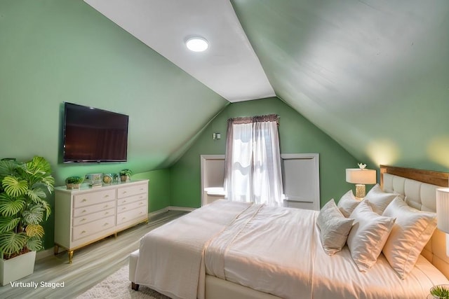 bedroom featuring light wood-type flooring, baseboards, and vaulted ceiling