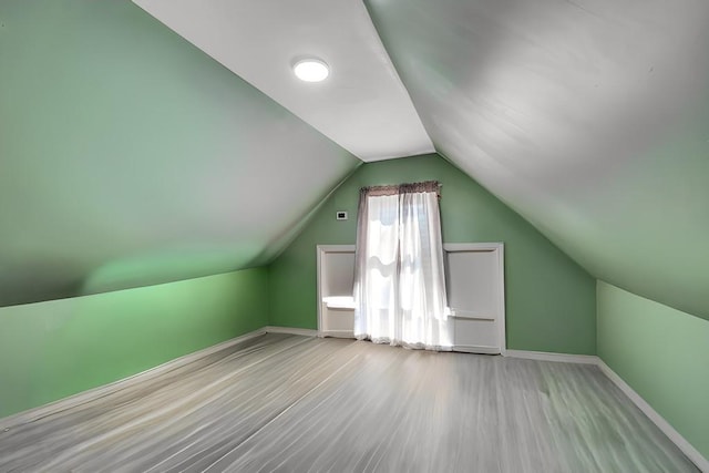 additional living space featuring lofted ceiling, baseboards, and wood finished floors