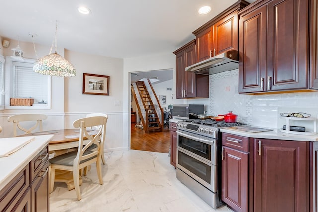 kitchen with range with two ovens, under cabinet range hood, marble finish floor, light countertops, and wainscoting