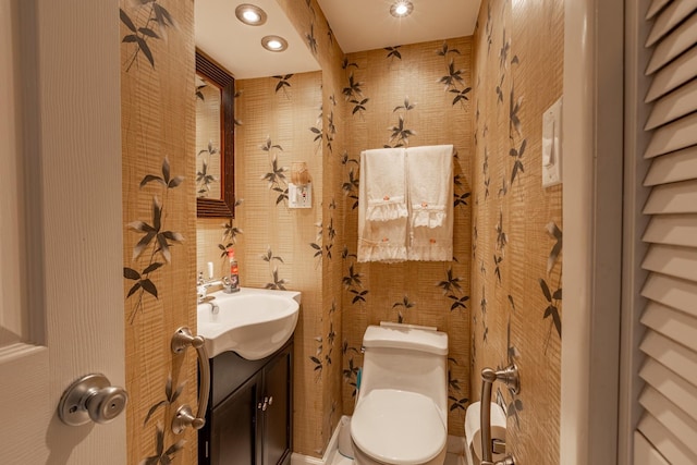 half bath featuring recessed lighting, vanity, and toilet