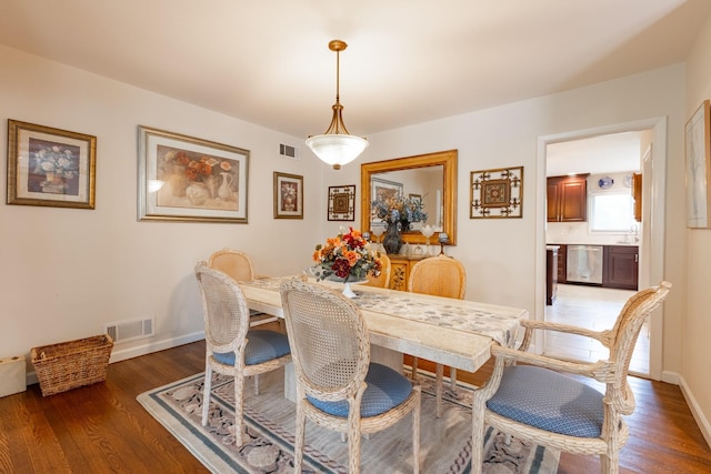 dining space with light wood-style flooring, visible vents, and baseboards