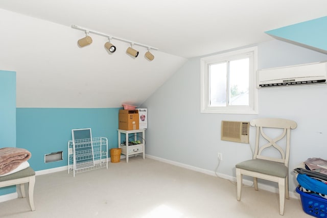 interior space with lofted ceiling, rail lighting, a wall mounted AC, carpet flooring, and baseboards