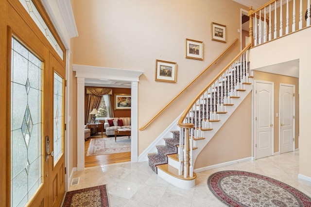 foyer entrance featuring marble finish floor, baseboards, visible vents, and a high ceiling