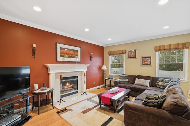 living room featuring light wood-style floors, recessed lighting, crown molding, and a premium fireplace